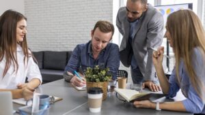 Profissionais em reunião colaborativa analisando como escolher a melhor empresa de team building em equipe, representando um ambiente de trabalho alinhado à cultura ágil.